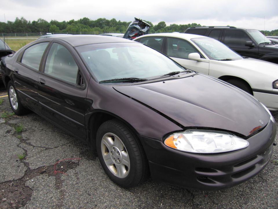 Dark purple sedan with hood ajar, parked outdoors on cracked asphalt