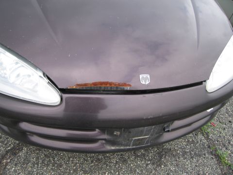 2001 Ford Crown Victoria - Front view of a dark purple car showing rust damage on the hood and a dented bumper.