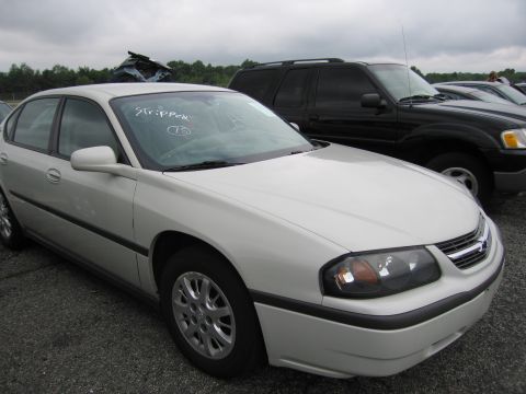 2001 Ford Crown Victoria - A white sedan is parked in a lot next to a black SUV, with "Stripper" written on its windshield.