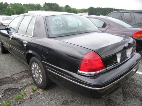 2001 Ford Crown Victoria - Rear view of a black 2001 Ford Crown Victoria sedan parked in an outdoor lot with other vehicles.