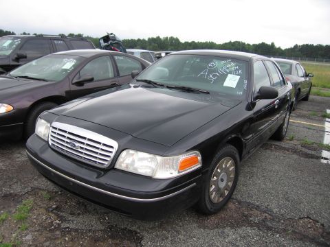 2001 Ford Crown Victoria - A black 2001 Ford Crown Victoria is parked in a lot with other vehicles, showing its front 3/4 view.