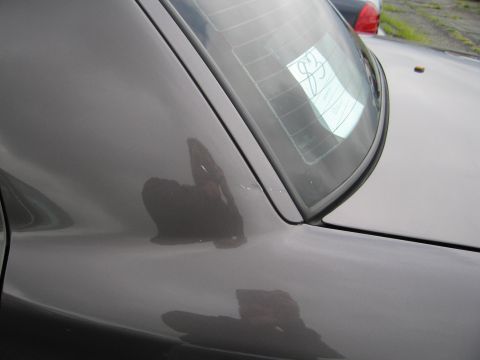 2001 Ford Crown Victoria - Reflection of photographer and a paper with '83' on the rear window of a dark sedan.
