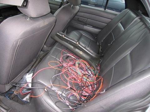 2001 Ford Crown Victoria - A tangled mess of electrical wires covers the rear seat of the vehicle.