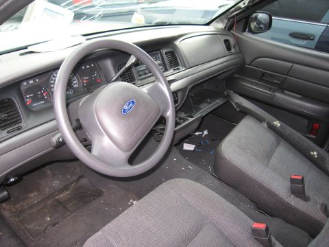 2001 Ford Crown Victoria - The interior of a 2001 Ford Crown Victoria shows a dirty dashboard and seats, with some parts appearing to be removed.