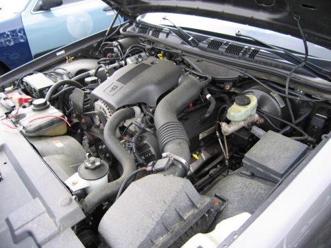 2001 Ford Crown Victoria - The engine bay of a 2001 Ford Crown Victoria is shown, with another vehicle visible in the background.