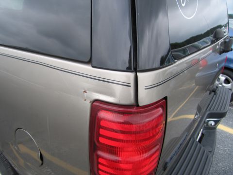 2001 Ford Crown Victoria - Rear view of a tan Ford Expedition showing damage to the quarter panel.