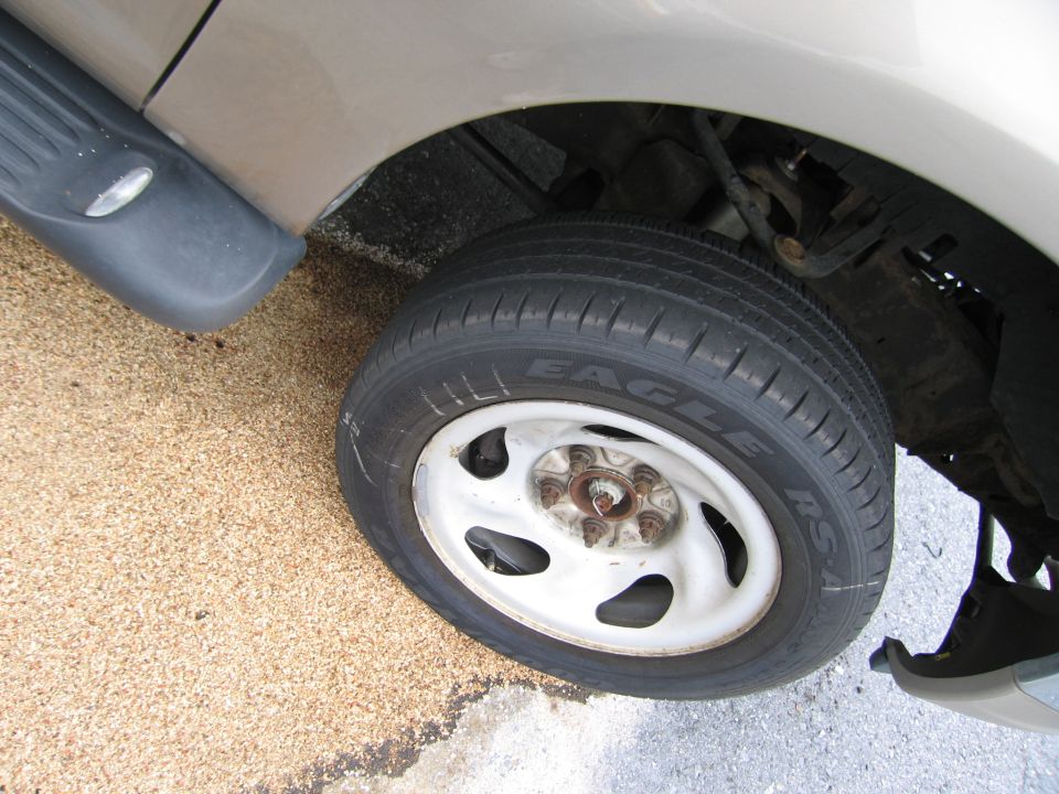 Close-up of a tan vehicle's front wheel and fender with a black running board