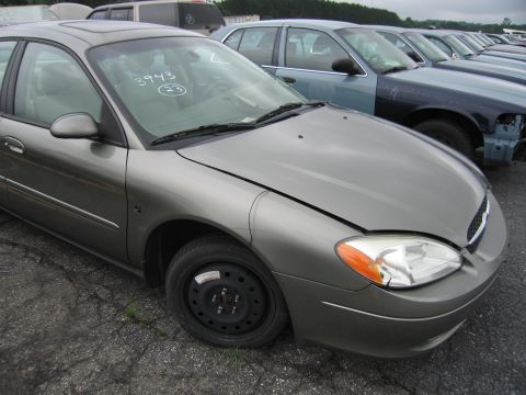 2001 Ford Crown Victoria - Gray Ford Taurus in a lot with other vehicles. Numbers written on windshield.