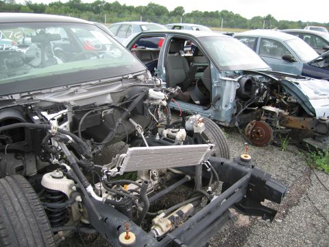 2001 Ford Crown Victoria - Junkyard scene with multiple stripped-down car frames and visible engine parts.