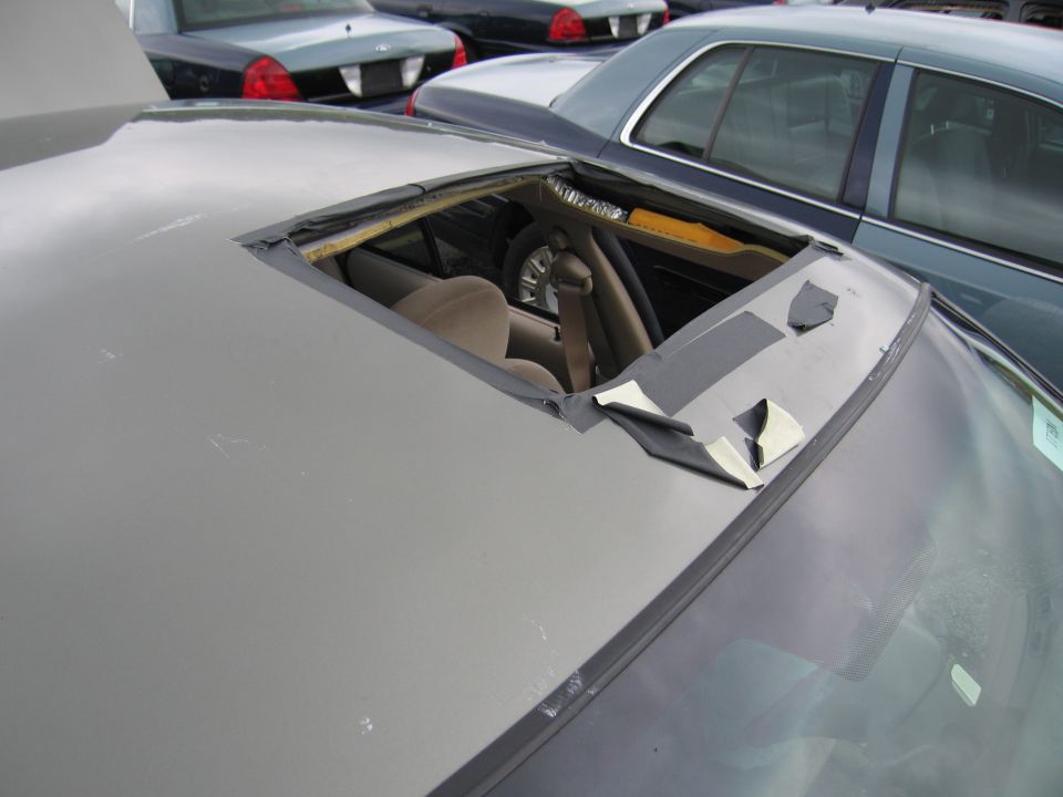 Damaged sunroof interior of a car, with other cars visible in background