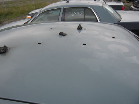 2001 Ford Crown Victoria - The photo shows the roof of a car with multiple holes, and another vehicle in the background.