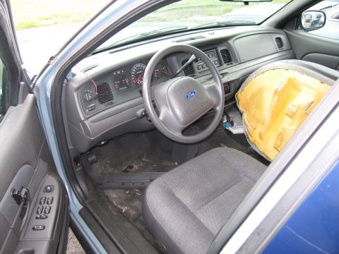 2001 Ford Crown Victoria - The interior of a 2001 Ford Crown Victoria is visible, with the driver's side door open and the airbag deployed.