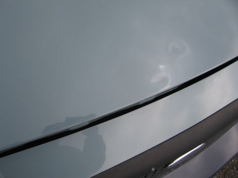 2001 Ford Crown Victoria - Close-up of a dented light blue car hood with visible paint damage.