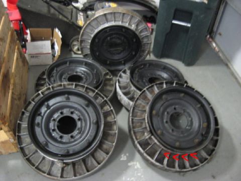 1991 Ford Bronco - Multiple large vehicle wheels with distinctive finned rims are stored indoors.