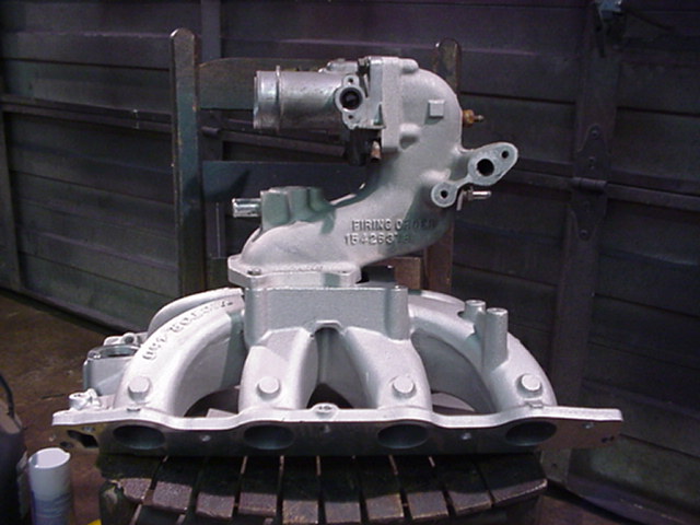 Silver engine intake manifold with 'FIRING ORDER 1-3-7-2-6-5-4-8' stamped on it