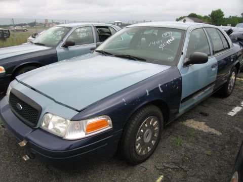 2001 Ford Crown Victoria - Photo of a two-tone blue Ford Crown Victoria sedan with auction markings at a lot.