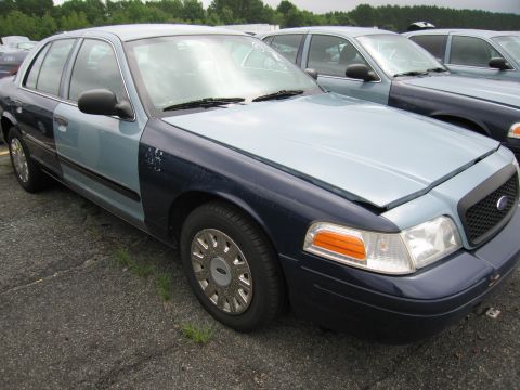 2001 Ford Crown Victoria - Photo of a two-tone blue Ford Crown Victoria sedan parked among cars in an auction lot.