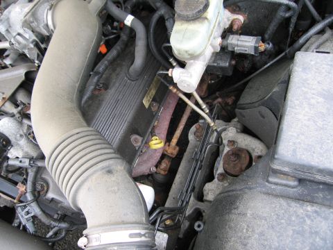 2001 Ford Crown Victoria - Close-up photo of an engine's intake tube, hoses and valve covers in the bay.