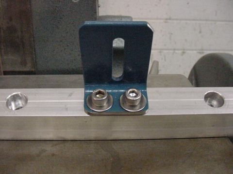 1979 Ford Bronco - A blue metal bracket is secured to an aluminum rail with two bolts.