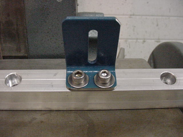 Blue metal bracket attached with two bolts to a silver aluminum rail