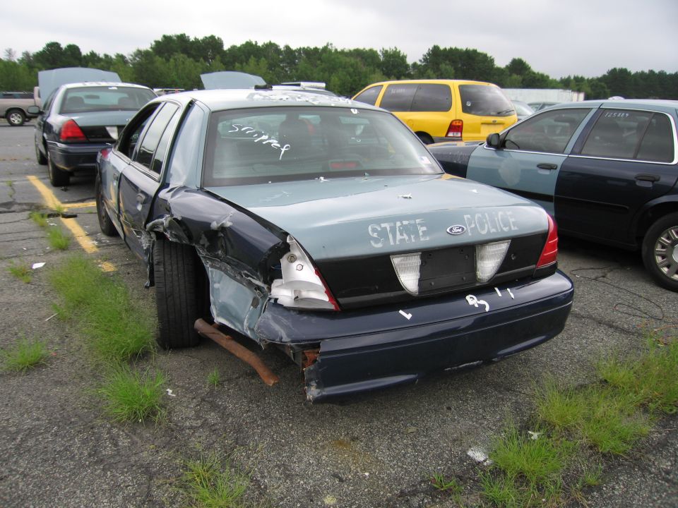 Wrecked blue State Police sedan in an auction lot