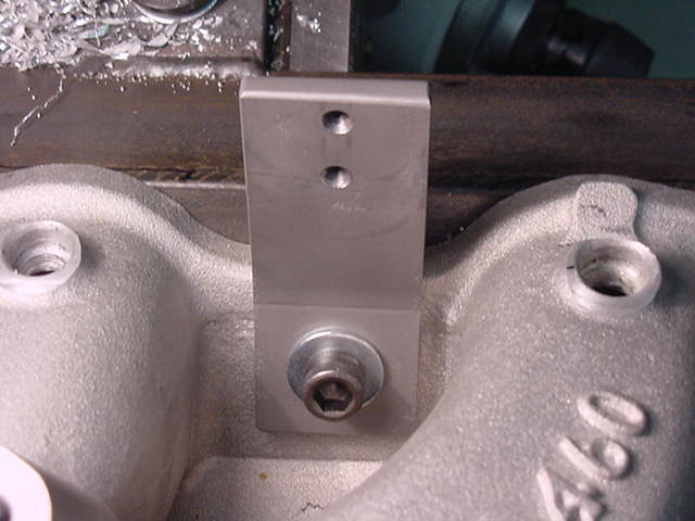 Metal bracket bolted to a textured engine intake manifold part