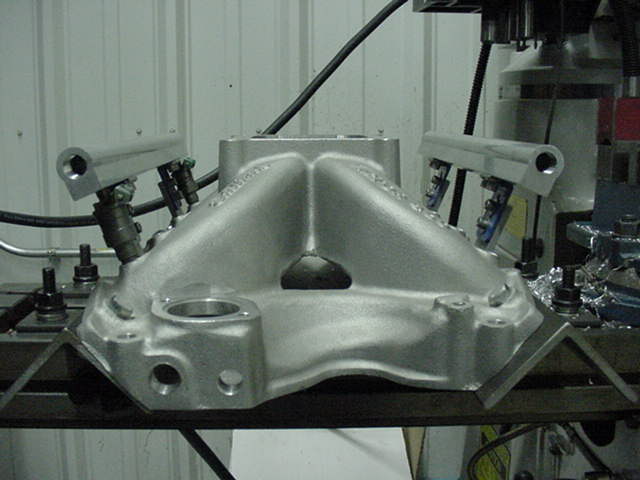Aluminum intake manifold with fuel injectors mounted on a workbench