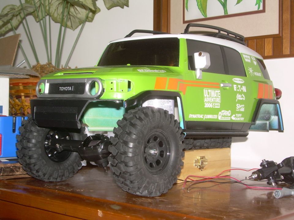 Green RC Toyota FJ Cruiser replica with large tires and visible wiring.