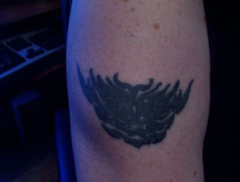 1994 Ford Bronco - A close-up shot of a dark-colored tattoo on a person's arm. The tattoo appears to be a stylized, possibly tribal, design.