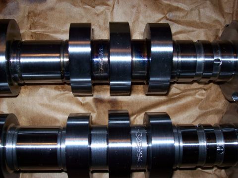2007 Ford Mustang - Two camshafts are shown laid out on brown paper. The top camshaft has the number "30995" etched into it, while the bottom camshaft has "1-3…
