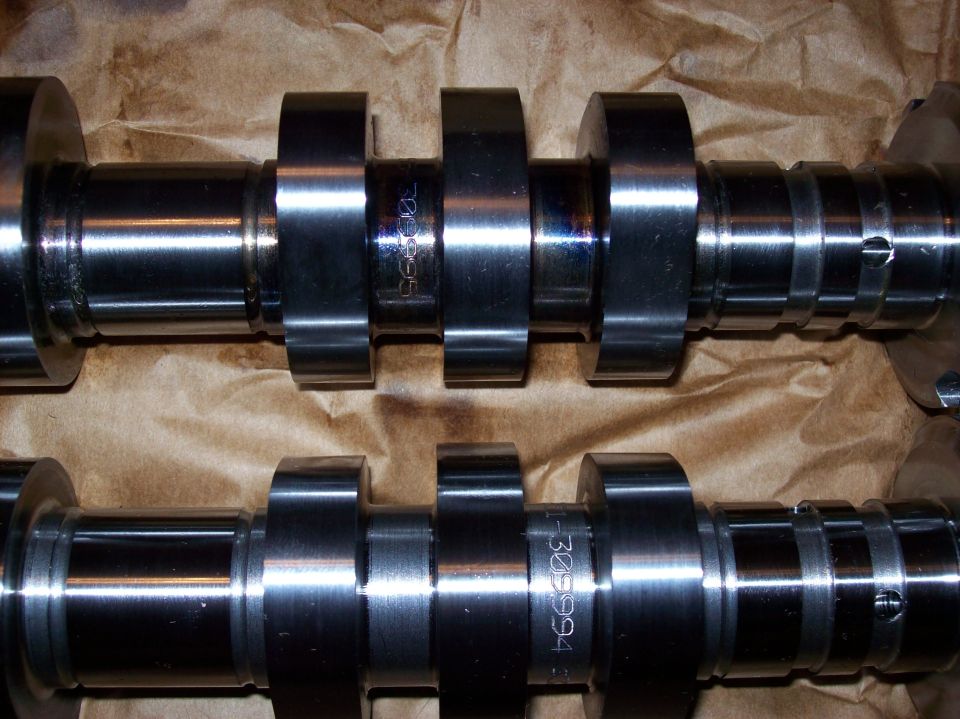 Two metal camshafts with etched numbers on brown paper.