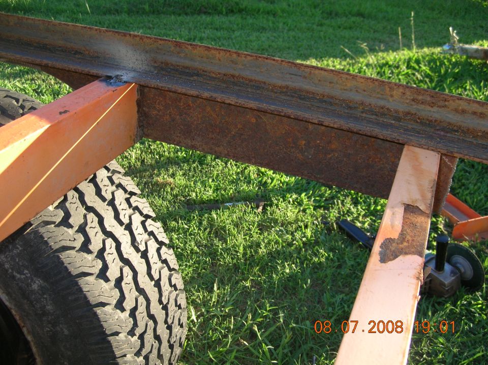 Close-up of rusty metal frame, orange support, and tire on grass.