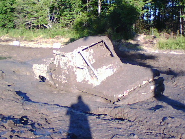 White pickup truck stuck in mud.