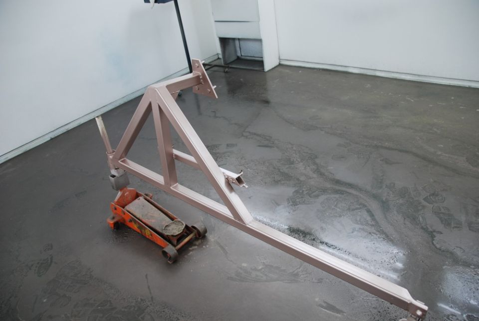 Primed fabricated triangular steel frame piece on a shop floor