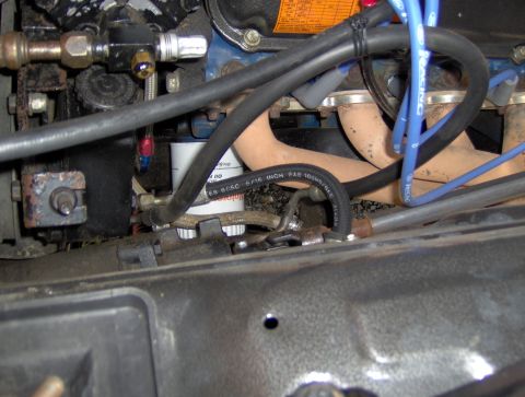 1978 Ford Bronco - Close-up view of engine components including spark plug wires, exhaust manifold, and an oil filter in a vehicle.