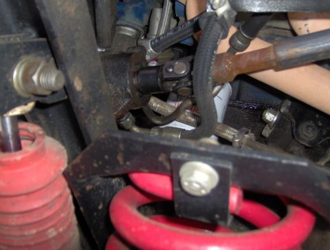 1978 Ford Bronco - A close-up view of the steering linkage and suspension components of a vehicle, likely a 1978 Ford Bronco. Visible parts include a U-joint,…