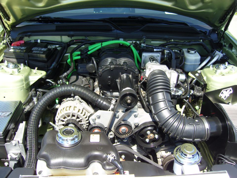 Modern Ford Mustang engine bay with supercharger and green vacuum hoses
