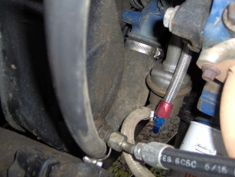 1978 Ford Bronco - A close-up view shows a braided fuel line with red and blue fittings connected to a fuel filter assembly. The surrounding area includes var…