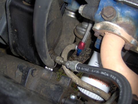 1978 Ford Bronco - A close-up view of engine bay components in a 1978 Ford Bronco, showing various hoses, metal lines, and a portion of the engine block and e…