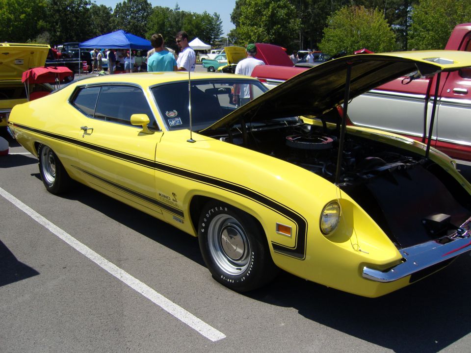 Yellow 1970 Ford Torino fastback with black stripes at a car show