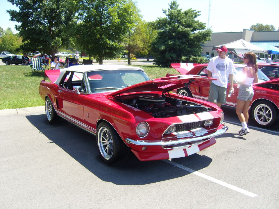 Red Shelby GT350 Mustang convertible at a car show with hood open