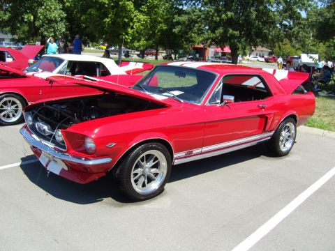 2007 Ford Mustang - A red 1967 Ford Mustang coupe is displayed with its hood open at a car show, alongside other vehicles.