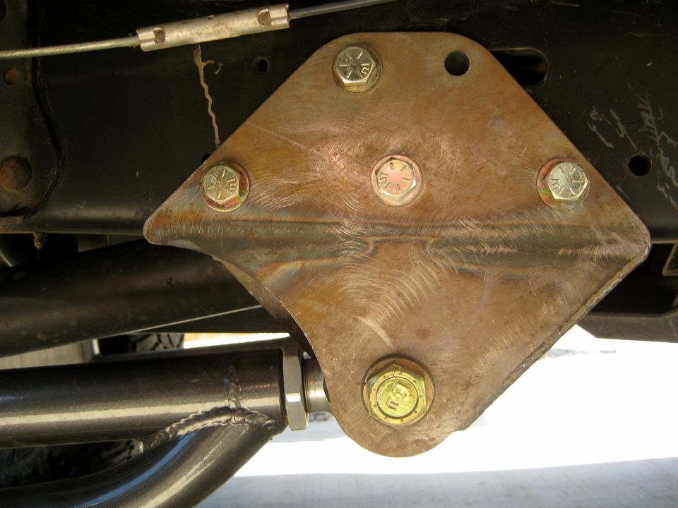 Custom fabricated steel bracket bolted to vehicle frame with four bolts, part of front suspension