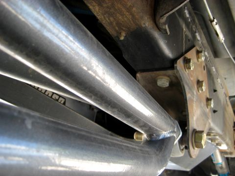 1996 Ford Bronco - Underside view of a vehicle's suspension system, showing metal bars and bolted components.