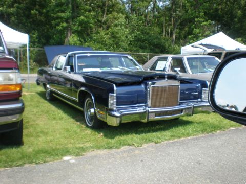 1988 Mercury Grand Marquis - A dark blue Lincoln Continental Mark VI is parked on grass with its hood open, next to other vehicles.