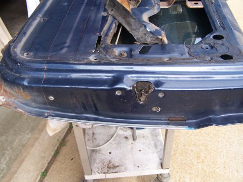 1986 Ford Bronco - Close-up of a damaged blue car door, revealing the interior latch mechanism and signs of rust.