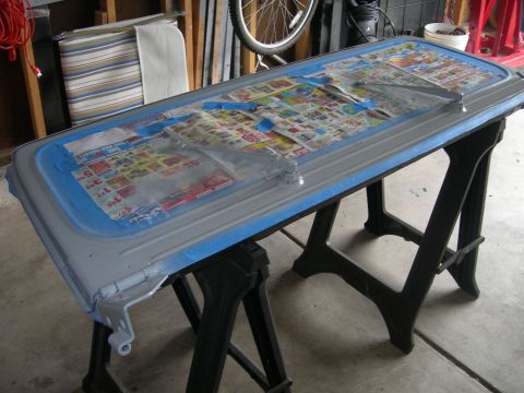1991 Jeep Wrangler - A car door is prepared for painting, covered with tape and newspaper, and placed on sawhorses in a garage.
