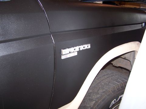 1986 Ford Bronco - Close-up of the fender and wheel well of a 1986 Ford Bronco, showing the vehicle's emblem.