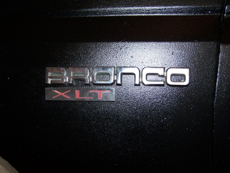 Bronco XLT emblem on black textured surface