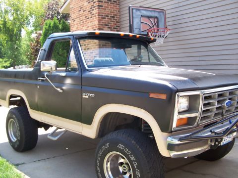 1986 Ford Bronco - This lifted Ford Bronco has a two-tone paint scheme and sits parked in a driveway.